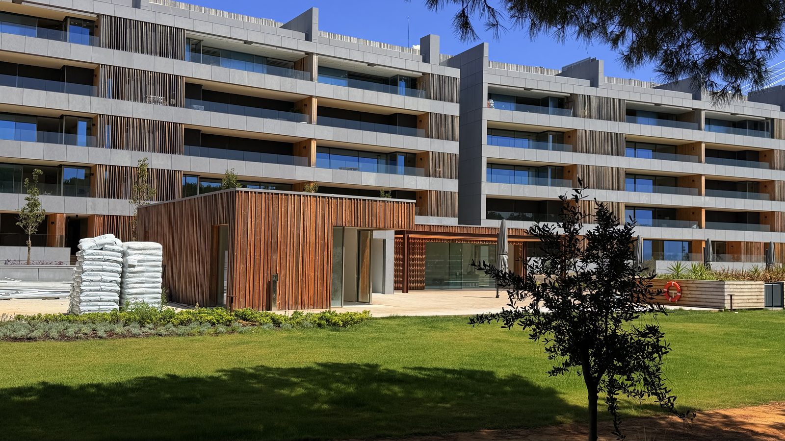 Piscina exterior com deck de madeira e Ponte Vasco da Gama ao fundo